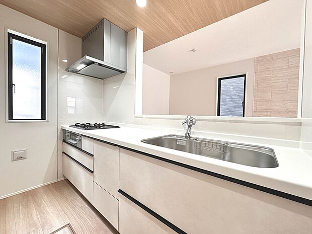【キッチン】 三口コンロで料理の幅を拡げてくれる使いやすいシステムキッチンを採用。洗い場も大きいので野菜や食器を洗ったりする際にも捗り、奥様の強い味方となってくれるはずです。