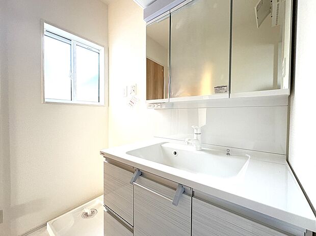 【2号棟 洗面台】上部に吊り戸収納・3面鏡の小物収納、引き出しと扉収納を備えたシャンプードレッサー