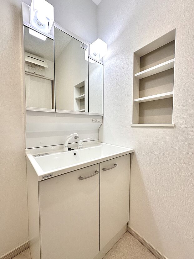 【D号棟 洗面台】三面鏡の収納の他 小物棚、右手にカウンターのあるユーティリティースペース