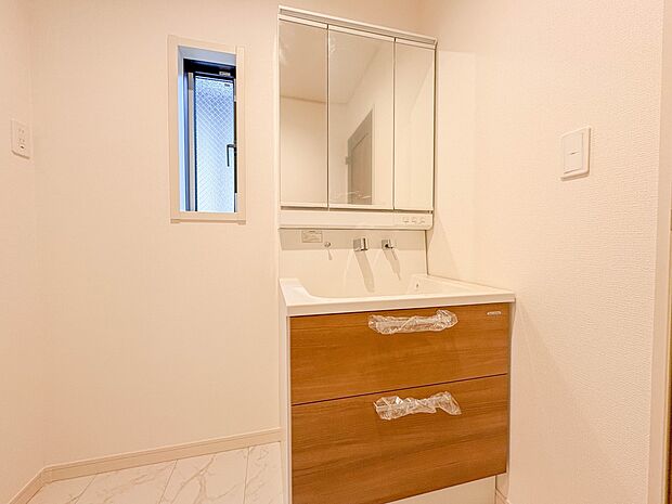 2号棟【三面鏡洗面化粧台】  ミラーを手前に引けば、楽な姿勢で髭剃りやメイクができます。合わせ鏡にすればヘアスタイルのチェックもラクラク。洗面化粧台のミラー裏にはたっぷり入る収納スペースを設…