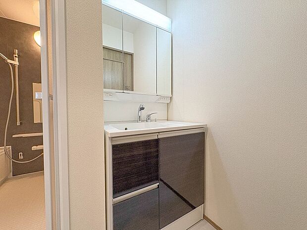 A号棟【洗面台】大きく見やすい三面鏡で清潔感ある洗面台は、身だしなみチェックや肌のお手入れに最適です。何かと物が増える場所だからこそ、スッキリと見映えの良い空間に拵えました。