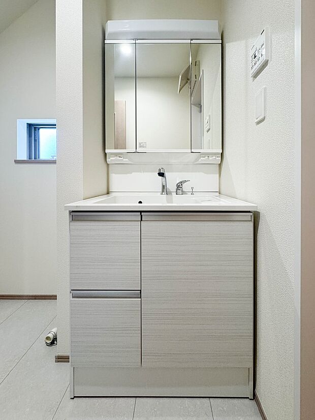A号棟【洗面所】大きく見やすい三面鏡で清潔感ある洗面台は、身だしなみチェックや肌のお手入れに最適です。何かと物が増える場所だからこそ、スッキリと見映えの良い空間に拵えました。