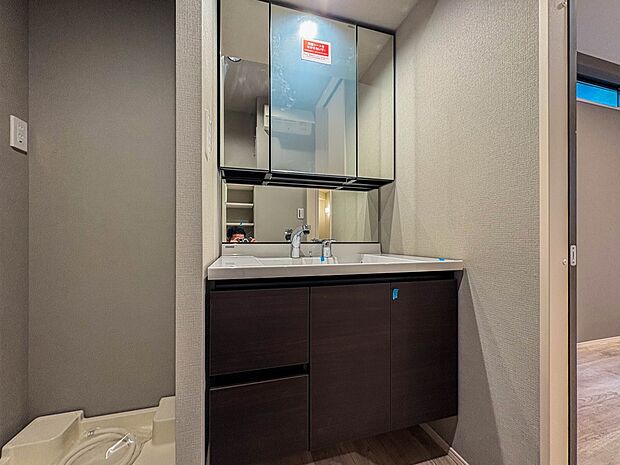 1号棟【三面鏡洗面化粧台】  ミラーを手前に引けば、楽な姿勢で髭剃りやメイクができます。合わせ鏡にすればヘアスタイルのチェックもラクラク。洗面化粧台のミラー裏にはたっぷり入る収納スペースを設…