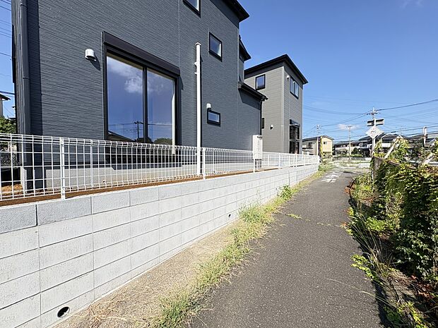 【2号棟 現地外観】北東側は遊歩道・自然豊か、穏やかな住環境（写真  手前2号棟 奥1号棟