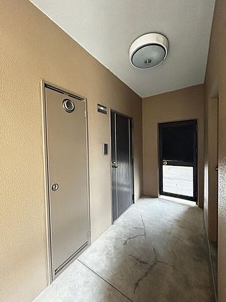 【リフォーム済み】エレベーターを降りて右手にございます、玄関外写真です。写真奥の扉からバルコニーへつながっており、行き来できる仕様になっております。ペットとの散歩の行き帰り等あると便利な扉ですね。