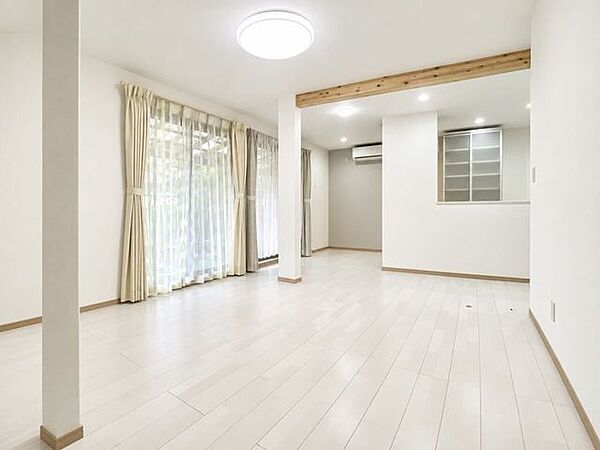 キッチン側から見た16帖のLDK。白い床と壁が室内をより明るく広く演出し、家具の配置もしやすいすっきりとした空間です。キッチン側の壁にはエアコンが1台設置されております。
