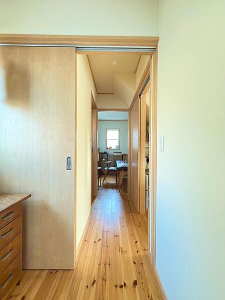 明るい木目で統一された廊下。無垢のフローリングが肌触り良く、奥の部屋まで心地よい空間が続きます。バリアフリー設計の引き戸を採用。明るく開放的な廊下で移動も快適。
