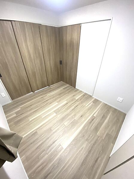 お部屋のコーディネートがしやすいシンプルな形状の洋室です。壁一面に配置された収納スペースは開口部が広く、衣類や日用品を効率よく整理できます。プライベートな時間を快適に過ごせる独立空間です。