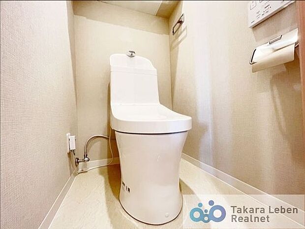 暖色照明と柔らかいアクセントクロスの落ち着けるトイレ。吊戸棚、温水洗浄シャワー付きです。