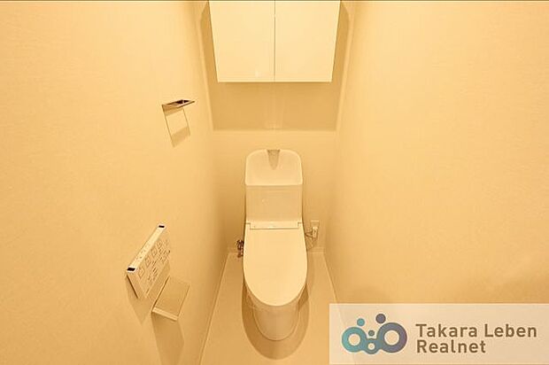 吊戸棚を設けた温水洗浄トイレ。白で統一した清潔感ある空間です。