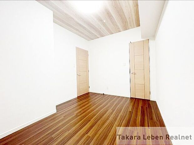 約5.5帖の洋室2。天井と床にトーンの違う木目調を使用。サイドには白にすることで、広く感じられます。洋室1とは違うデザインになっています。
