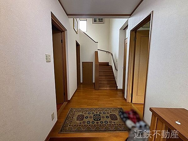 明るい陽光が差し込む玄関ホールは、住まいの温かさを感じさせる空間です。木目調のフローリングと手すりが温もりを添えています。