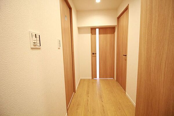 リビングドアの縦スリットから柔らかな光が差し込む、明るく爽やかな廊下スペース。帰宅した瞬間に我が家の温もりと開放感に包まれる、家族やゲストを優しく迎え入れてくれる心地よい動線設計です。