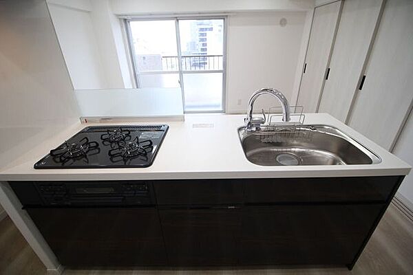 お部屋全体を見渡せる開放感あふれる対面スタイルのシステムキッチンです。スタイリッシュなダークトーンの下部収納と清潔感のあるホワイト天板が美しく調和しています。