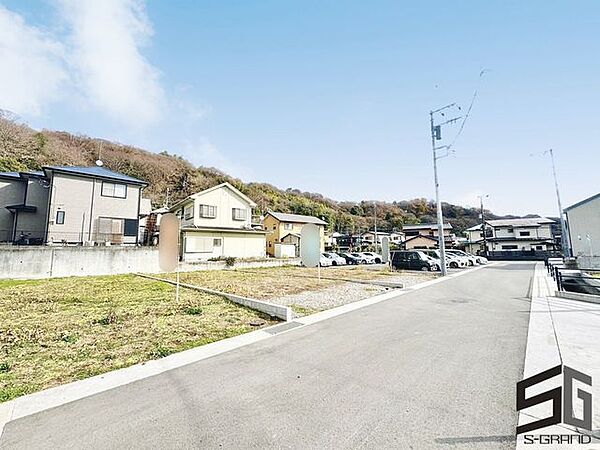 広々とした前面道路に面し、車の出し入れがしやすい現地外観。ゆとりある駐車スペースと開放感のある立地が魅力で、毎日の暮らしに快適さと安心をもたらすマイホームです。