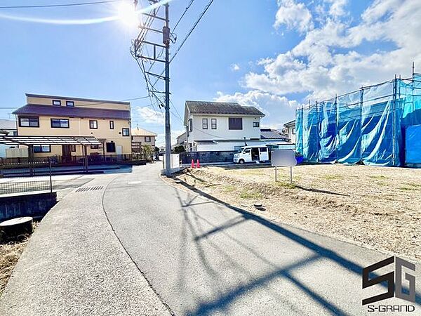 広々とした前面道路に面し、車の出し入れがしやすい現地外観。ゆとりある駐車スペースと開放感のある立地が魅力で、毎日の暮らしに快適さと安心をもたらすマイホームです。