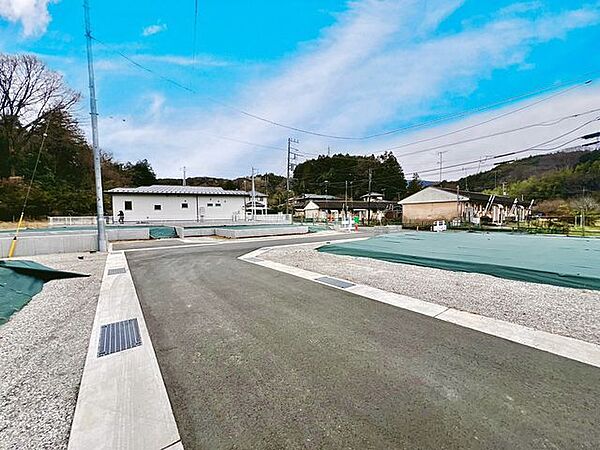 広々とした前面道路に面し、車の出し入れがしやすい現地外観。ゆとりある駐車スペースと開放感のある立地が魅力で、毎日の暮らしに快適さと安心をもたらすマイホームです。