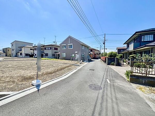 広々とした前面道路に面し、車の出し入れがしやすい現地外観。ゆとりある駐車スペースと開放感のある立地が魅力で、毎日の暮らしに快適さと安心をもたらすマイホームです。