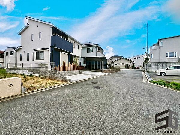 広々とした前面道路に面し、車の出し入れがしやすい現地外観。ゆとりある駐車スペースと開放感のある立地が魅力で、毎日の暮らしに快適さと安心をもたらすマイホームです。