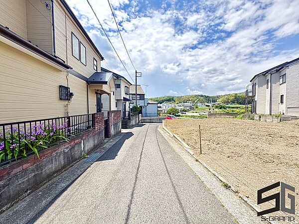 広々とした前面道路に面し、車の出し入れがしやすい現地外観。ゆとりある駐車スペースと開放感のある立地が魅力で、毎日の暮らしに快適さと安心をもたらすマイホームです。