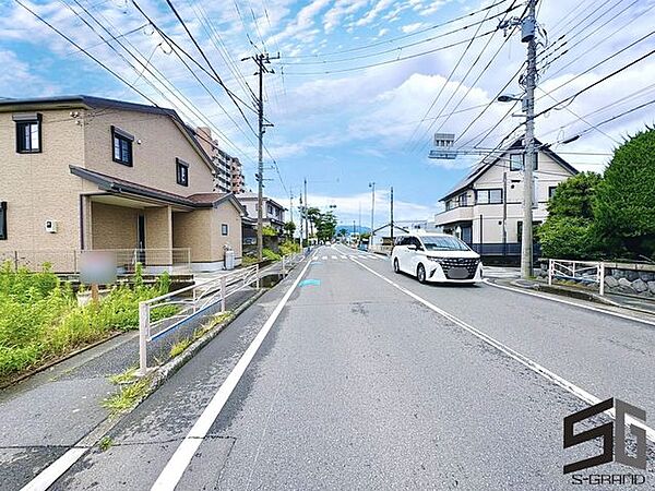広々とした前面道路に面し、車の出し入れがしやすい現地外観。ゆとりある駐車スペースと開放感のある立地が魅力で、毎日の暮らしに快適さと安心をもたらすマイホームです。