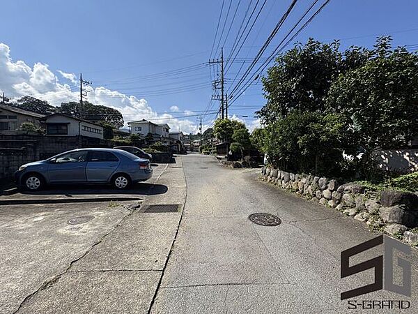 広々とした前面道路に面し、車の出し入れがしやすい現地外観。ゆとりある駐車スペースと開放感のある立地が魅力で、毎日の暮らしに快適さと安心をもたらすマイホームです。