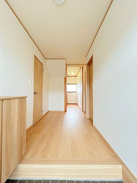 【リフォーム済み】1階廊下です。床はフローリング重ね張り、壁・天井はクロス貼り替えを行いました。階段下部分にも収納がございます。