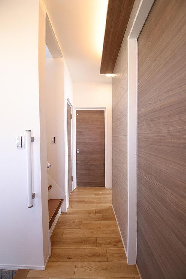 【玄関ホール・廊下】室内ドアはウォールナット柄の落つきのある色調。今回のリノベーションで玄関上がりには手すりを設置。小さな部品ですが大切な役割を担います。トイレは玄関より直接見えない場所にあります。