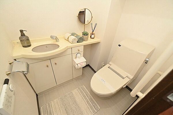 手洗いカウンター付きのゆとりあるトイレ空間です。吊戸棚があるためストック品もすっきりと収納可能。温水洗浄便座完備で清潔感のある仕上がりです。※CG加工しております。