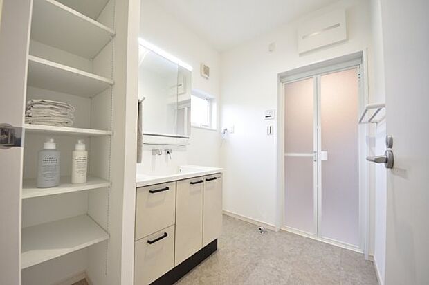 キッチンと合わせたアイボリーの洗面化粧台のある洗面脱衣室　高さを変えられる可動棚付き