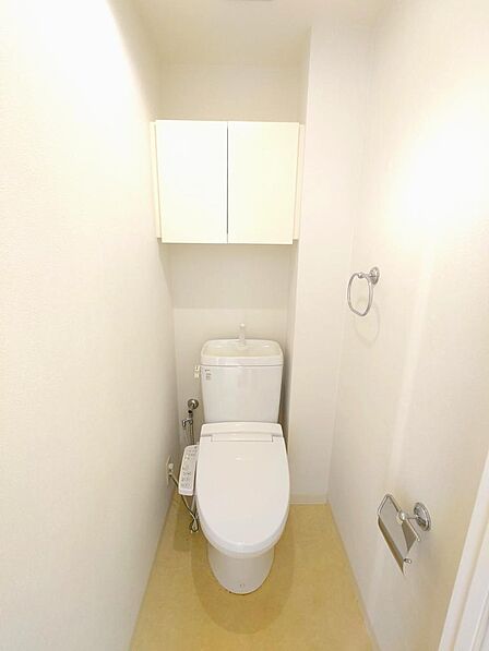 温水洗浄便座付きのトイレです。上部に収納棚があり、備品もすっきり片付きます。清潔感のある落ち着いた空間です。