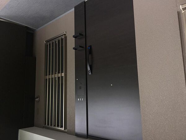 110号室の玄関まわりの様子です。落ち着いた色合いの玄関ドアの手前には奥行きのあるポーチが設けられ、共用部側には面格子付きの窓を配置しています。ゆとりを感じられる住戸まわりとなっています。