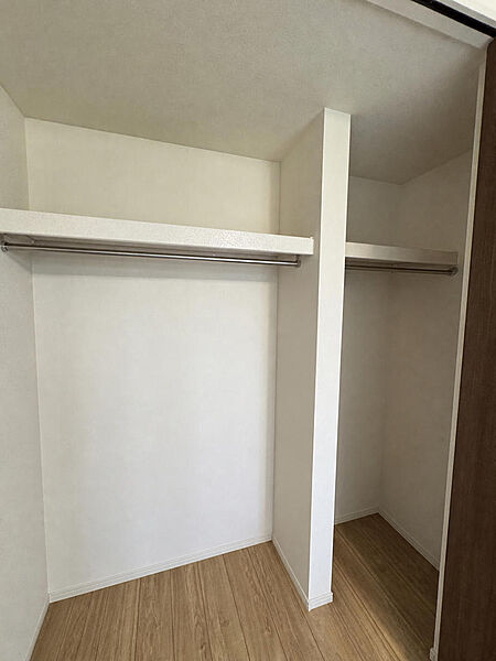 洋室のクローゼットです。ハンガーパイプが2列に分かれており、ご家族の衣類をまとめて掛けられます。上部の棚には帽子やバッグなどの小物も置いていただけます。