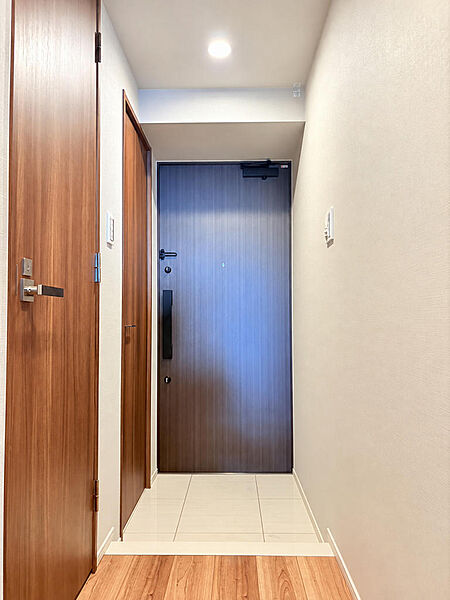室内側から見た玄関です。タイルの床と木目の建具が落ち着いた雰囲気をつくります。間取りにはシューズインクローゼットもあり、お出かけ用品の収納に活用できます。※AIによる家具消し加工を行なっております。