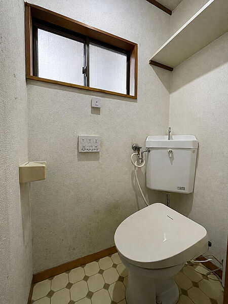 窓と収納棚を備えたトイレです。温水洗浄機能付き便座が設置され、日用品を置ける棚もあるため、実際の使い勝手を確認できます。日々の清掃にも配慮できます。※AIによる家具消し加工を行なっております。