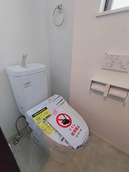 温水洗浄便座を備えたトイレで、手洗い器付きの機能的な設備。清潔感のある内装で、日常的に使いやすい落ち着いた雰囲気のトイレ空間です。