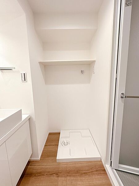 洗濯機置場。上段に収納棚があり、洗剤や消耗品などを収納できます