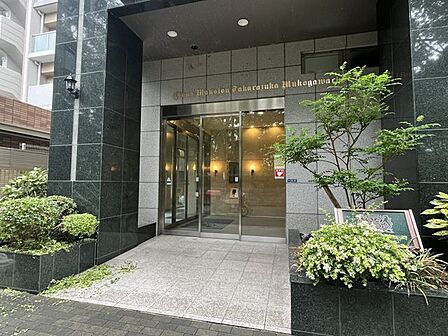 重厚感あふれる石張りの壁が迎えてくれるエントランスは、住まう方の品位を物語るデザインです 落ち着いた色調と豊かな植栽が調和し、日々の帰宅時間を特別なひとときへと変えてくれる上質な空間が広がります