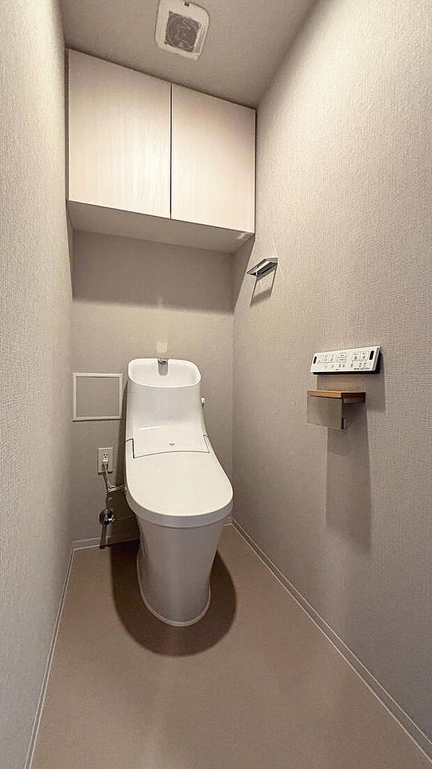 温水洗浄便座付きトイレ。上部に吊戸棚が設置されています。