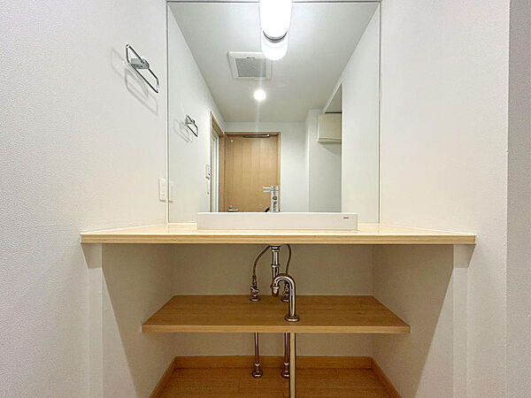 【Wash Room】ワイドミラーが空間に広がりを演出し、カウンターには身支度用品やインテリアをディスプレイできるゆとりを確保。木目のカウンターが温かみを添え、毎日の身支度を心地よい時間へと変えます。