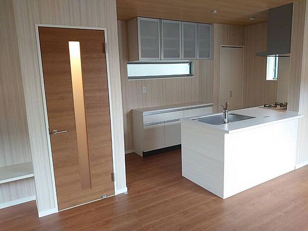 アイランド型のキッチンとカップボードとパントリー付き　茶色の床に白いキッチンが綺麗です