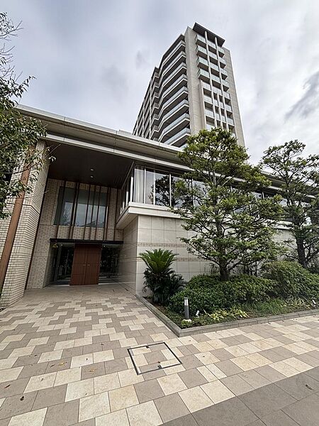 【エントランス・外観】総戸数360戸・15階建てのビッグコミュニティを象徴する重厚感溢れるエントランス。周囲を包む豊かな植栽が、日々の暮らしに心地よい潤いを与えます。