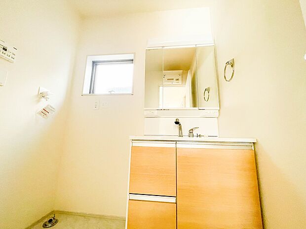 三面鏡洗面化粧台。ミラーを手前に引けば、楽な姿勢で髭剃りやメイクができます。合わせ鏡にすればヘアスタイルのチェックもラクラク。洗面化粧台のミラー裏にはたっぷり入る収納スペースを設けています。　