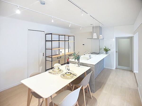 ダイニングをキッチンとひと続きに配置し、開放感のある空間に。白を基調とした明るい設えに、棚や照明のデザインがほどよく映え、食事も会話も心地よく楽しめます。