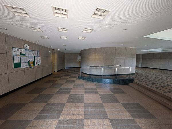 柔らかな光が差し込む開放的なロビーは、まるでお洒落なラウンジにいるような心地よさですね！チェック柄の床面がアクセントとなり、空間全体にモダンで軽やかなリズムを生み出していますね！