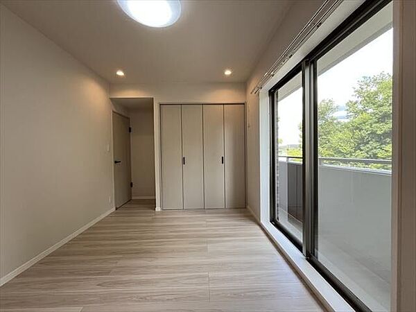 7帖：北側バルコニーに面した洋室。窓の外には緑が広がり、落ち着いた住空間です。