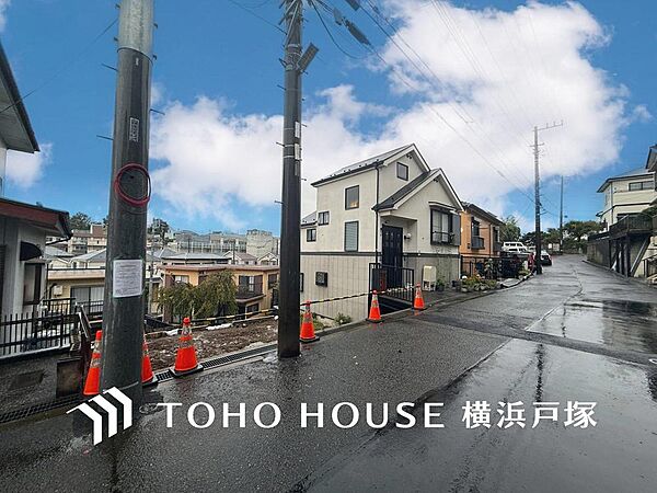 青空の下、白い外壁が映える美しい戸建て。坂道の多い閑静な住宅街は、家族で散歩を楽しみ、健やかな毎日を育む環境です。
