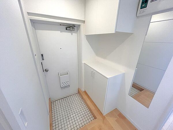 【帰るたび、少し気持ちが整う玄関】白を基調にまとめたすっきりとした玄関スペース。鏡付きでお出かけ前の身だしなみも確認しやすく、収納もコンパクトにまとまっています。