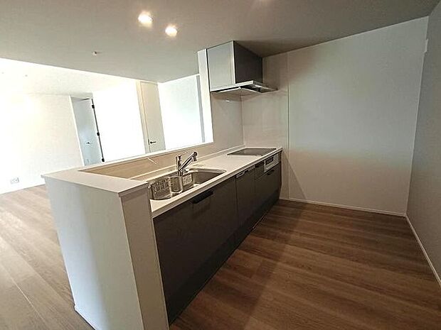 木目調の床と落ち着いた色味の収納が、空間にやさしい温もりを添えるキッチンです。使いやすい直線的なレイアウトで家事が進めやすく、リビングとのつながりが日々の時間を心地よく整えてくれます。