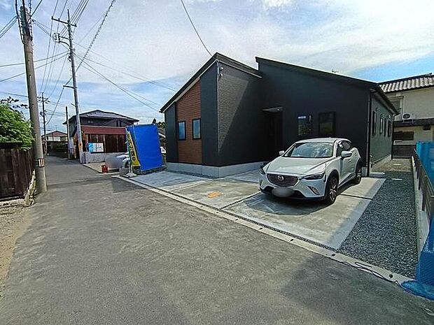 落ち着いたグレーと木目が調和するモダン平屋。前面道路はゆとりある幅で車の出入りもスムーズ。駐車スペースも広く、快適な暮らしを支える上質な住まいです。